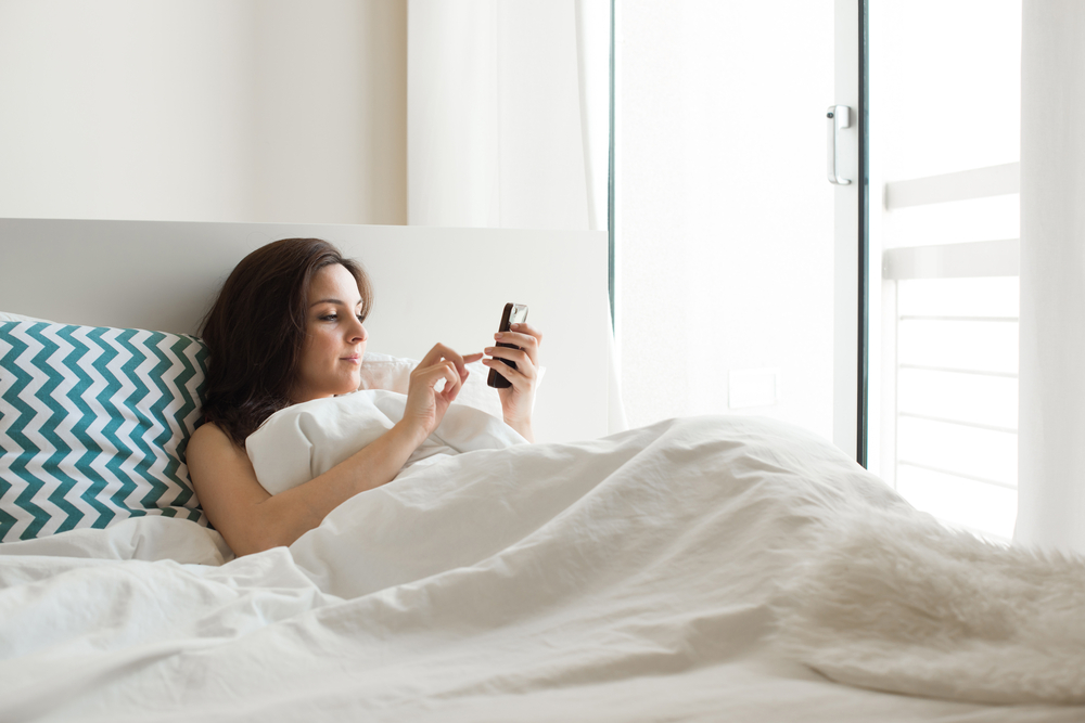 Woman smartphone bed