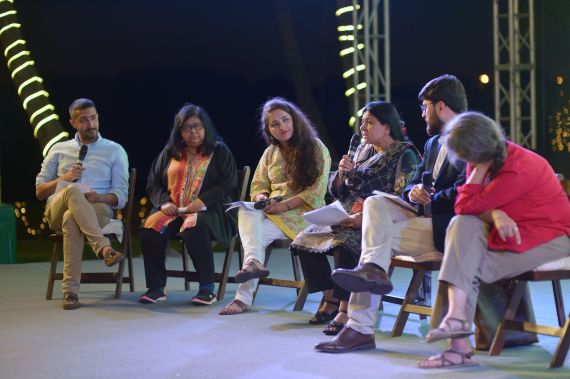 Six people sit on a stage in Karchi